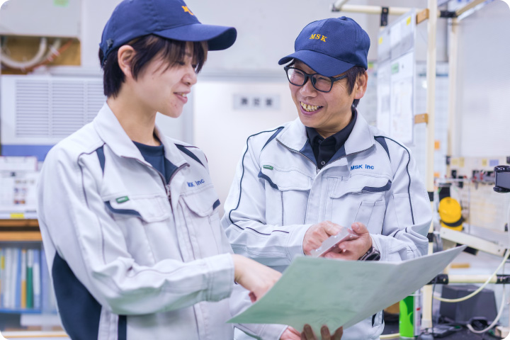 図面を確認しながら作業を教える先輩社員