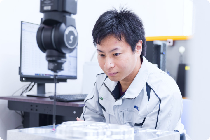 三次元測定機で製品の寸法を確認する社員